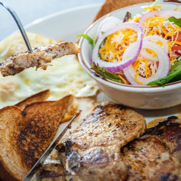 Grilled seasoned Pork Chops with two eggs, seasoned potatoes, and toast at Tasty Munch