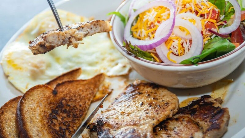 Grilled seasoned Pork Chops with two eggs, seasoned potatoes, and toast at Tasty Munch