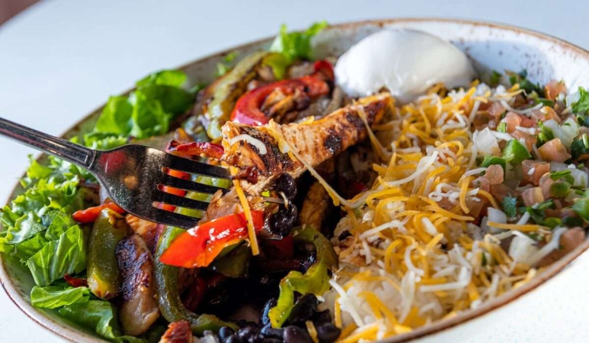 Grilled chicken bowl with rice, vegetables, and fresh toppings served at Tasty Munch in Houston.
