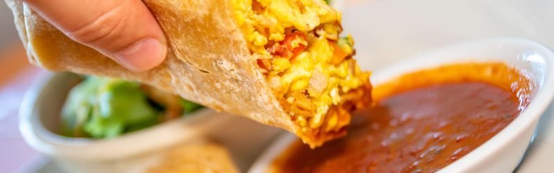 Breakfast burrito with eggs, cheese, and potatoes wrapped in a soft tortilla.